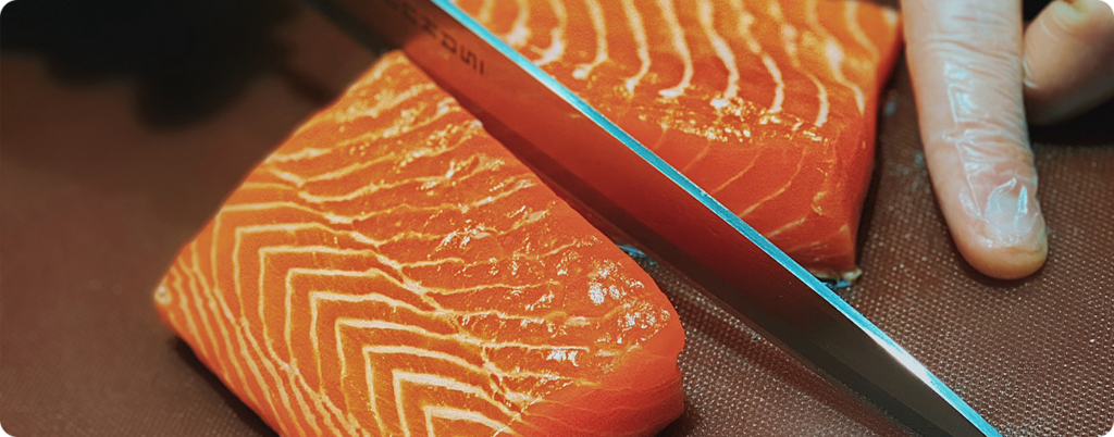 A chef slicing a piece of salmon 