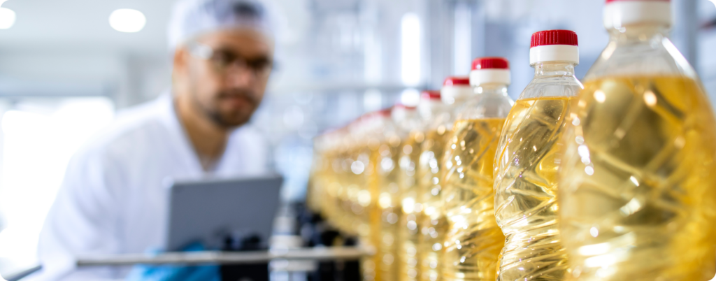 A factory worker inspecting a bottle of seed oils 