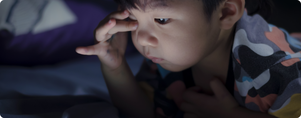 A young boy using a cell phone before bed 