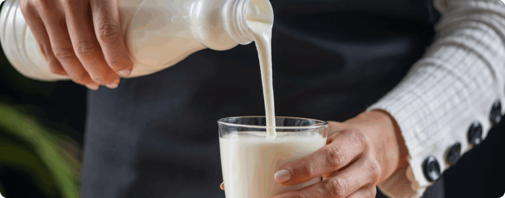 A woman pouring kefir into a glass