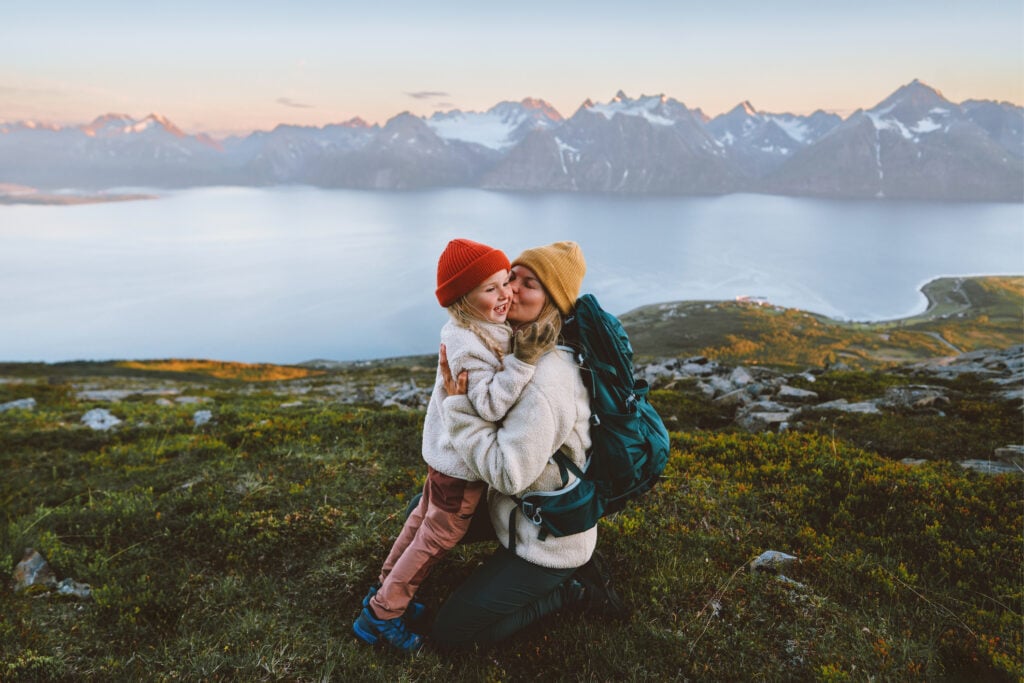 Family mother hiking with child in Norway travel vacations healthy lifestyle outdoor in mountains mom hugging kid daughter happy moments candid emotions